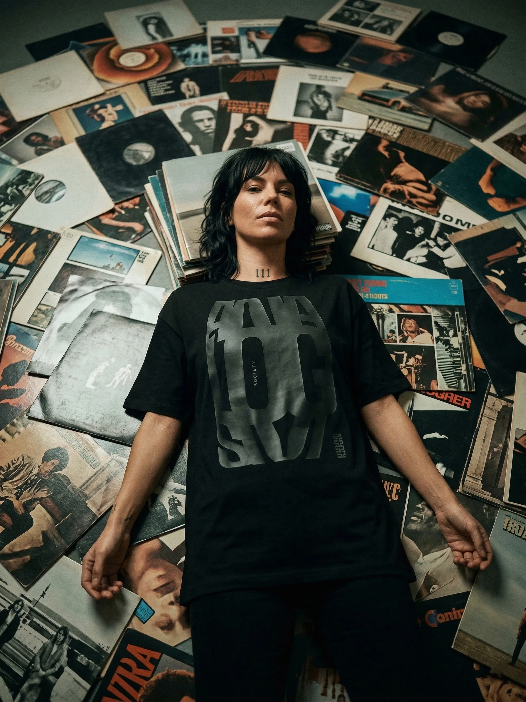 A woman wearing Analogism lies among a collection of vinyl records